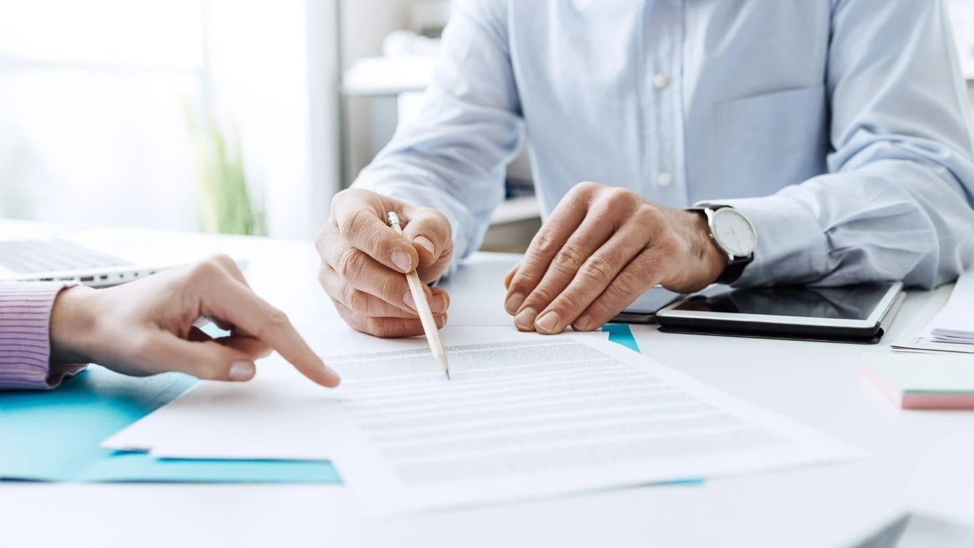 Two people are sitting at a table and one is holding a pencil