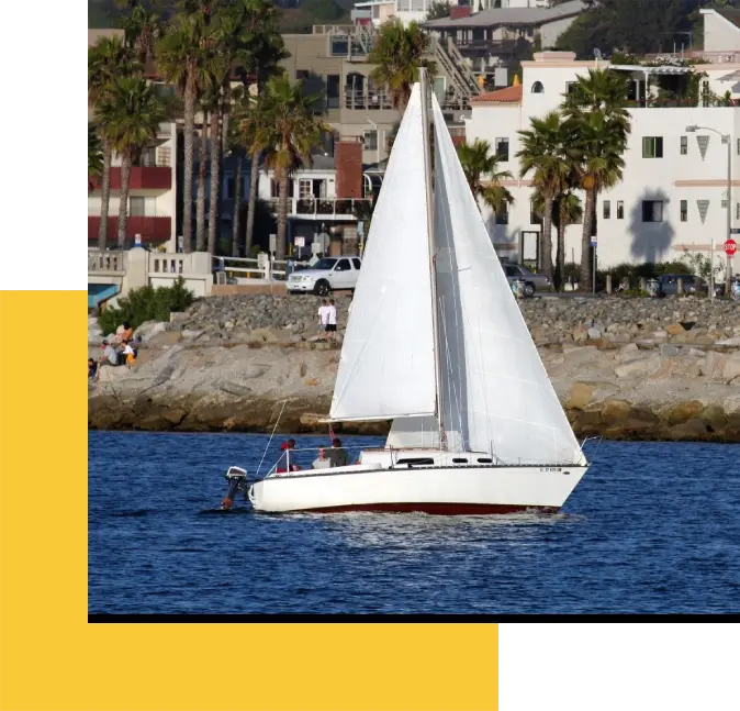 A sailboat in the water near some buildings.